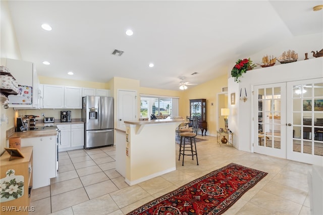 kitchen featuring ceiling fan, white cabinets, lofted ceiling, white appliances, and a breakfast bar