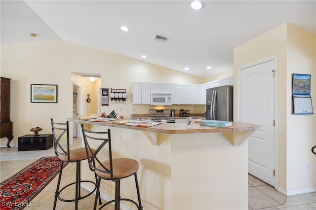 kitchen featuring white cabinetry, vaulted ceiling, a breakfast bar, stainless steel appliances, and a center island with sink