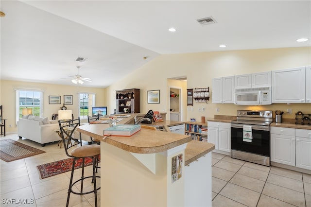 kitchen featuring ceiling fan, white cabinets, stainless steel range with electric stovetop, a breakfast bar, and vaulted ceiling