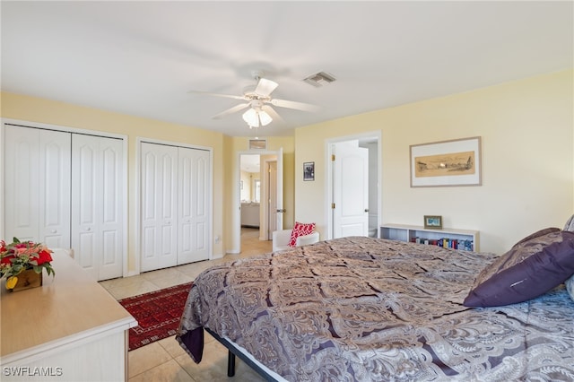 tiled bedroom with ceiling fan and multiple closets