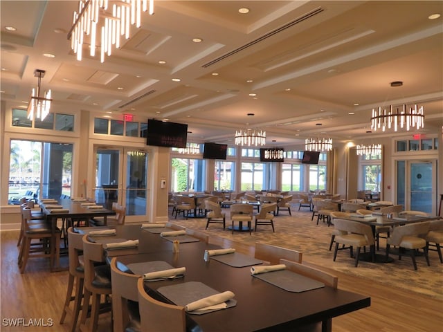 dining room with hardwood / wood-style floors, a chandelier, a wealth of natural light, and coffered ceiling