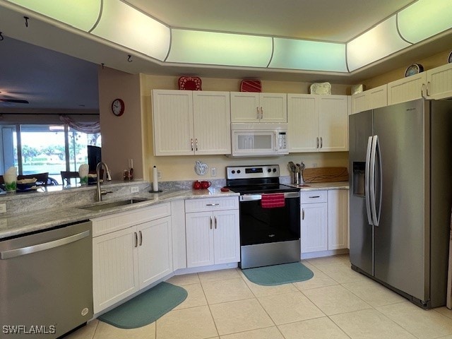 kitchen featuring light tile patterned floors, stainless steel appliances, sink, light stone counters, and white cabinets