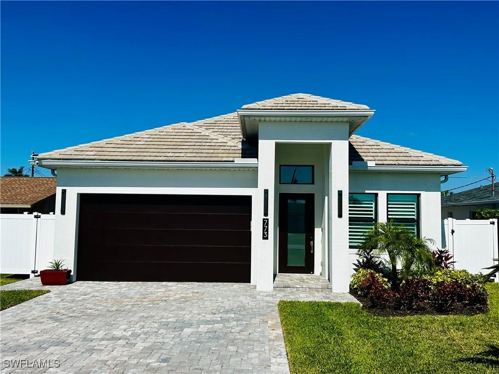 view of front of property with decorative driveway, fence, a garage, and stucco siding