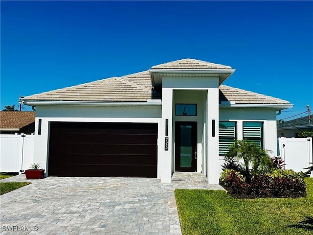 view of front of property with decorative driveway, fence, a garage, and stucco siding