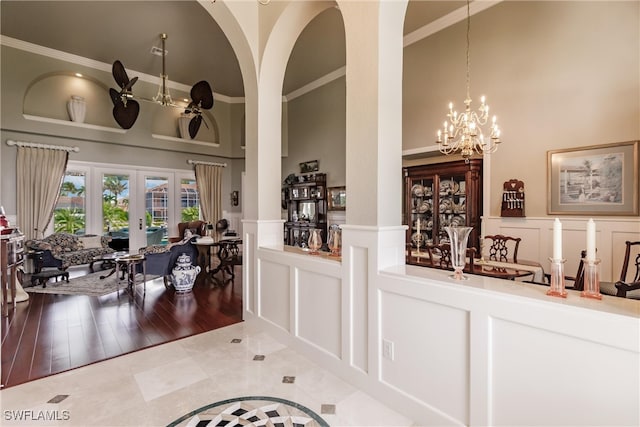 interior space with ornamental molding, french doors, a high ceiling, tile patterned floors, and a notable chandelier