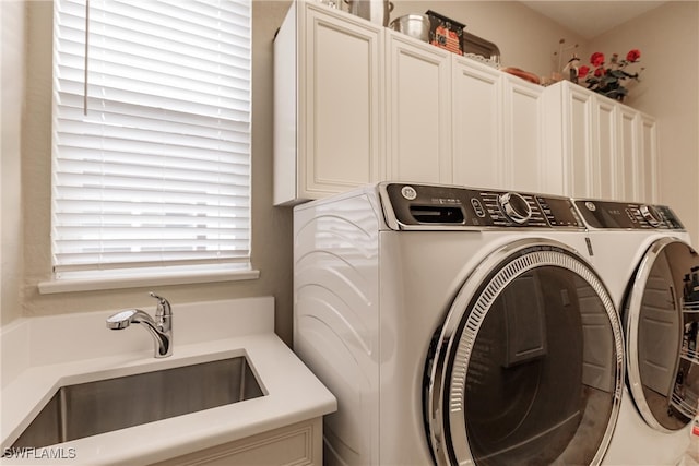 washroom with sink, washing machine and dryer, and cabinets