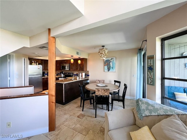 dining room featuring a chandelier and light stone finish flooring