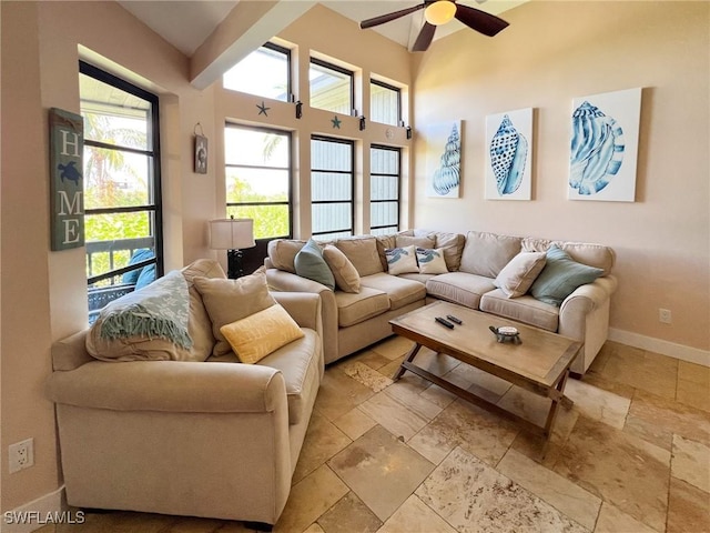 living area featuring stone tile flooring, a ceiling fan, and baseboards