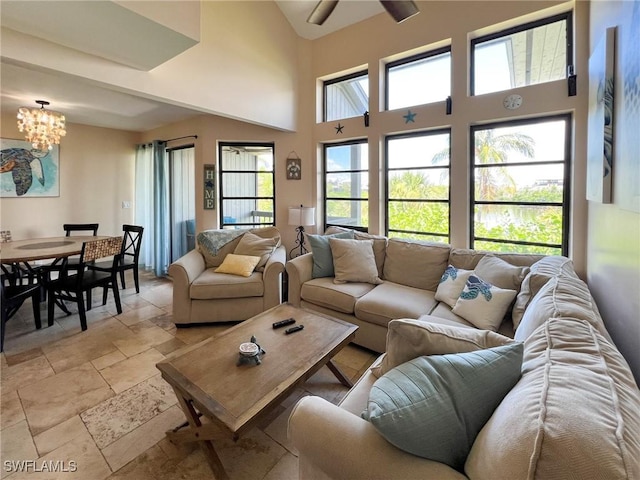 living area featuring a chandelier, stone tile flooring, and a high ceiling
