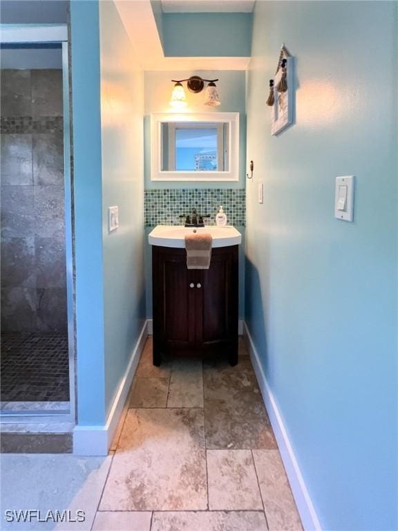 full bath featuring a stall shower, vanity, tasteful backsplash, and baseboards