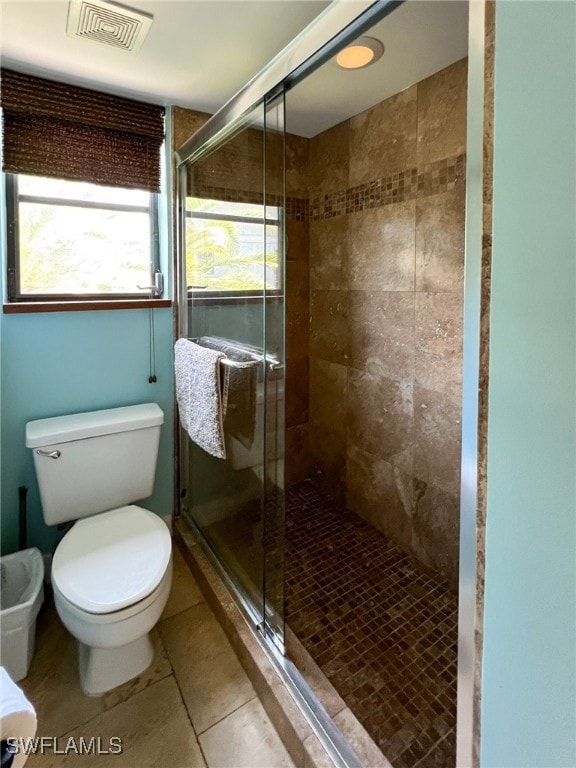 bathroom with tile patterned floors, toilet, and a shower with shower door