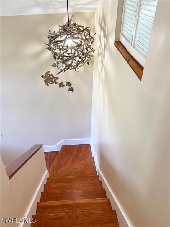 staircase featuring baseboards and a chandelier