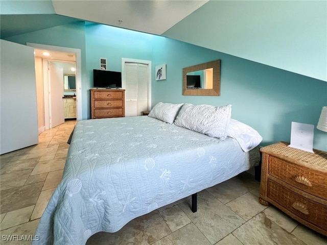bedroom featuring lofted ceiling, a closet, and stone finish flooring