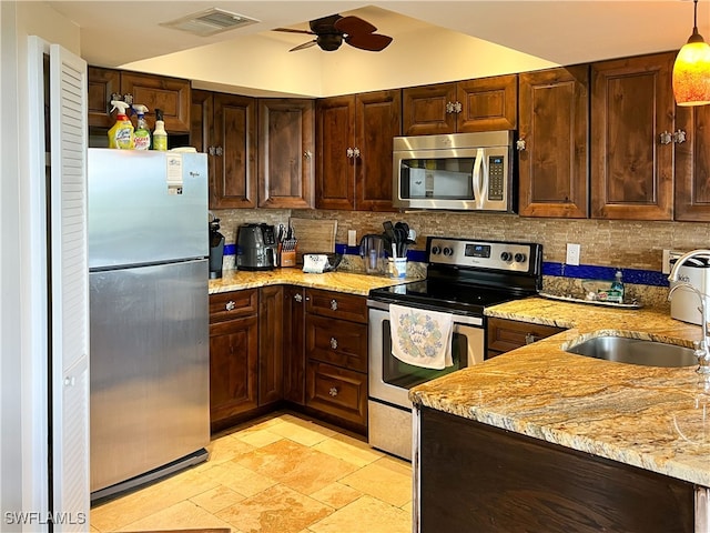 kitchen with stainless steel appliances, a sink, tasteful backsplash, a ceiling fan, and light stone counters