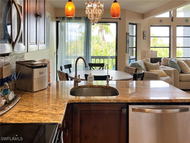 kitchen featuring light stone countertops, hanging light fixtures, stainless steel appliances, sink, and a chandelier