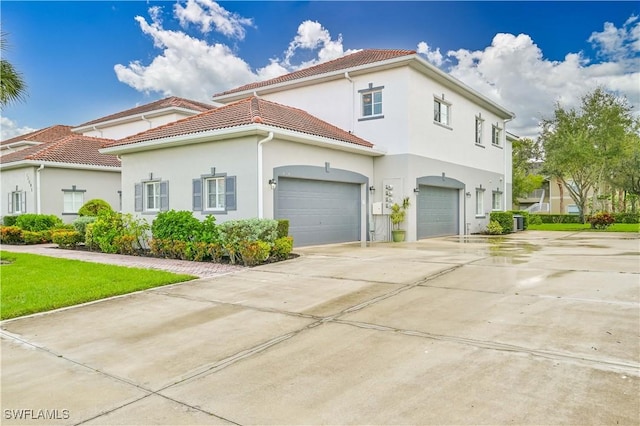 view of front of property featuring a garage, driveway, a tiled roof, and stucco siding