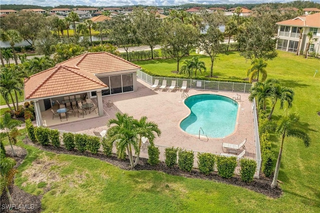 pool with a patio, a bar, a lawn, and fence