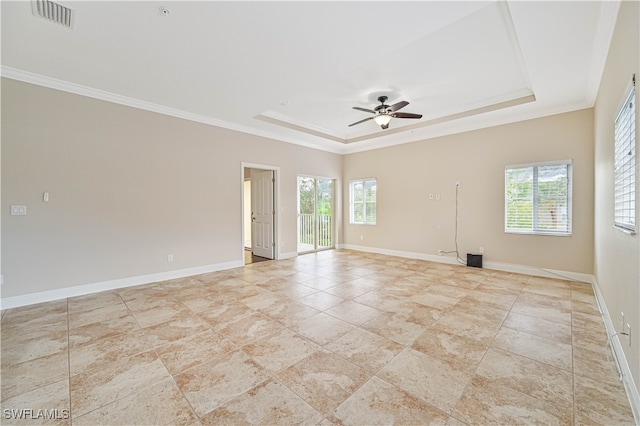 spare room with ornamental molding, ceiling fan, a tray ceiling, and plenty of natural light