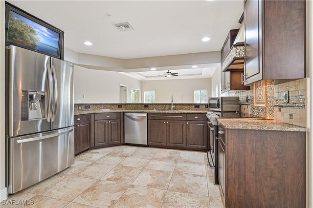 kitchen featuring ceiling fan, light stone countertops, sink, dark brown cabinetry, and stainless steel appliances