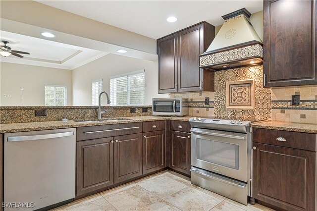 kitchen with light stone countertops, appliances with stainless steel finishes, sink, custom exhaust hood, and crown molding