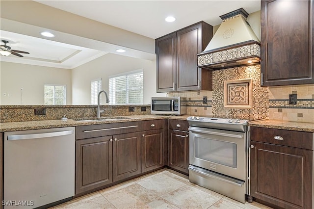 kitchen featuring custom exhaust hood, decorative backsplash, appliances with stainless steel finishes, a sink, and light stone countertops