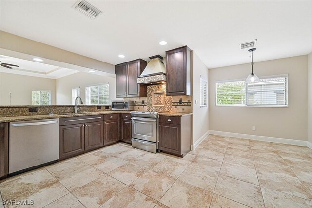 kitchen featuring sink, custom range hood, stainless steel appliances, and plenty of natural light