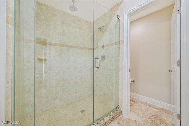 bathroom with a shower stall, baseboards, and tile patterned floors