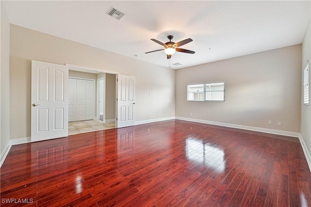 spare room featuring a ceiling fan, baseboards, visible vents, and wood finished floors