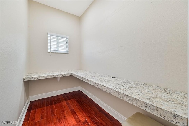 interior space with baseboards, built in desk, and wood finished floors