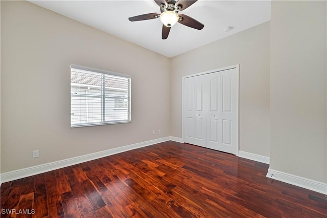 unfurnished bedroom with a closet, dark wood-style flooring, baseboards, and a ceiling fan