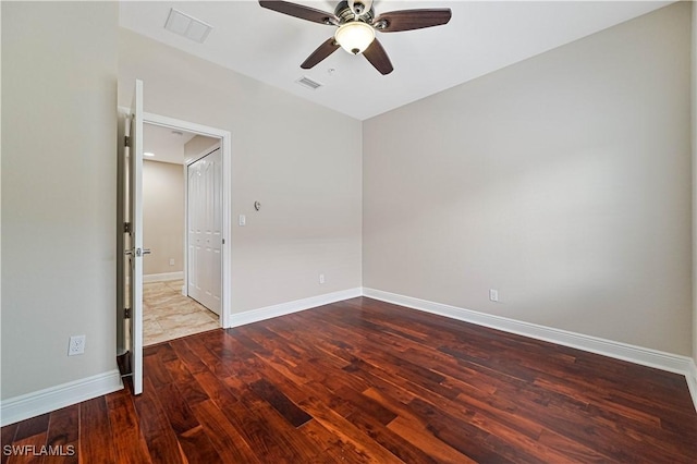 empty room featuring a ceiling fan, baseboards, visible vents, and wood finished floors