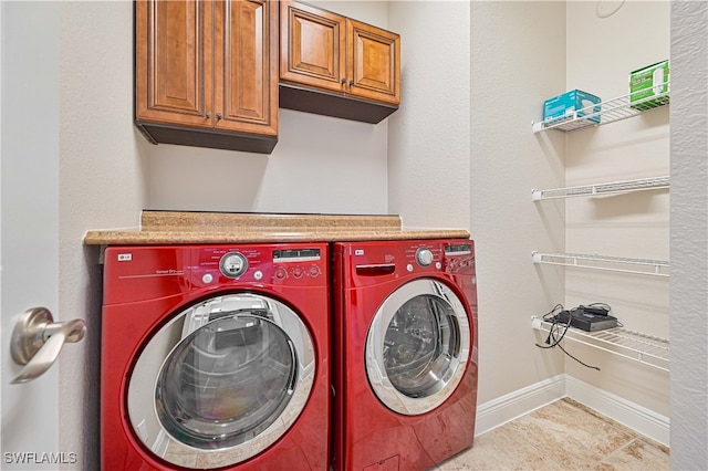 laundry room featuring cabinets, light tile patterned flooring, and washing machine and dryer