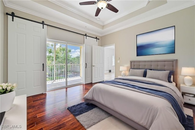 bedroom with a barn door, a raised ceiling, wood finished floors, access to exterior, and crown molding