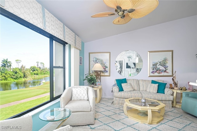 living room featuring ceiling fan, vaulted ceiling, and a water view