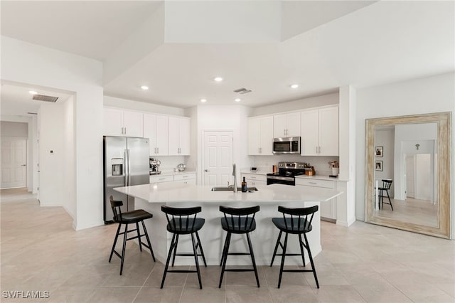 kitchen featuring white cabinets, stainless steel appliances, a kitchen island with sink, and sink