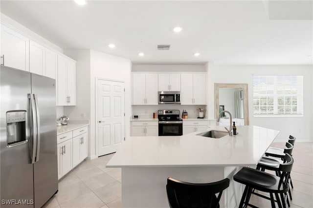 kitchen with stainless steel appliances, a center island with sink, light tile patterned flooring, and sink