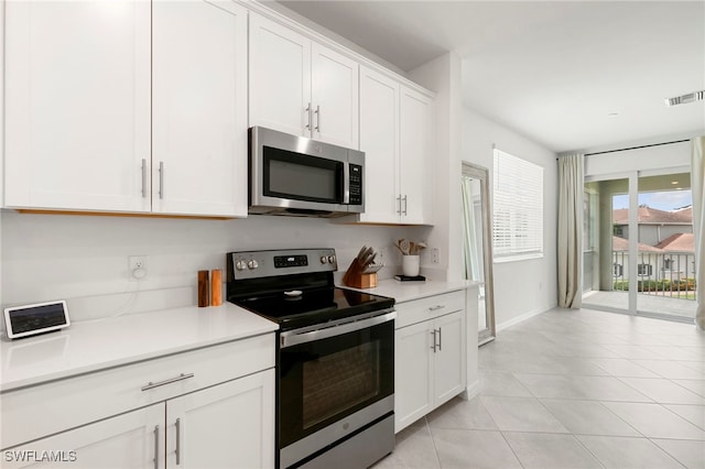 kitchen featuring appliances with stainless steel finishes, light tile patterned floors, and white cabinets