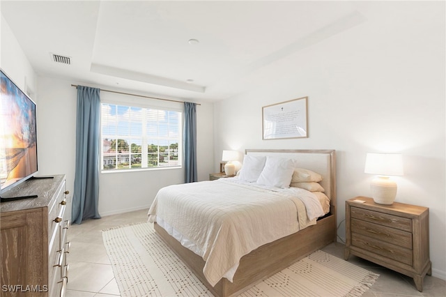 bedroom with a tray ceiling and light tile patterned flooring