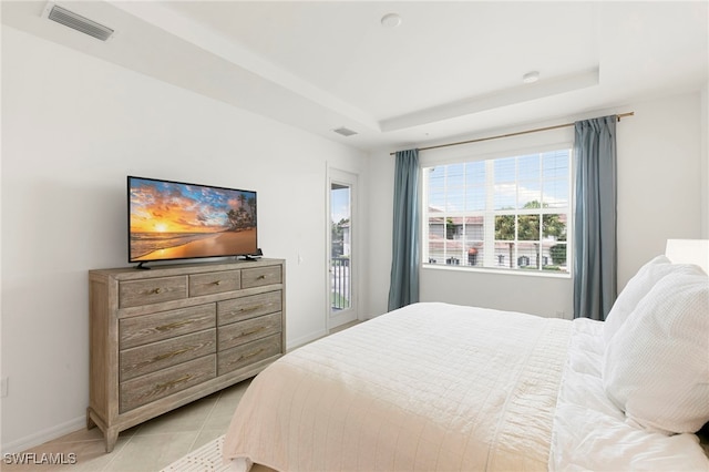 bedroom featuring a raised ceiling, access to exterior, and light tile patterned floors