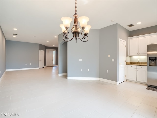 tiled empty room with an inviting chandelier