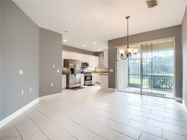 kitchen with a notable chandelier, stainless steel appliances, white cabinetry, and decorative light fixtures