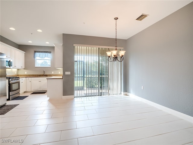 kitchen with hanging light fixtures, sink, white cabinetry, appliances with stainless steel finishes, and an inviting chandelier