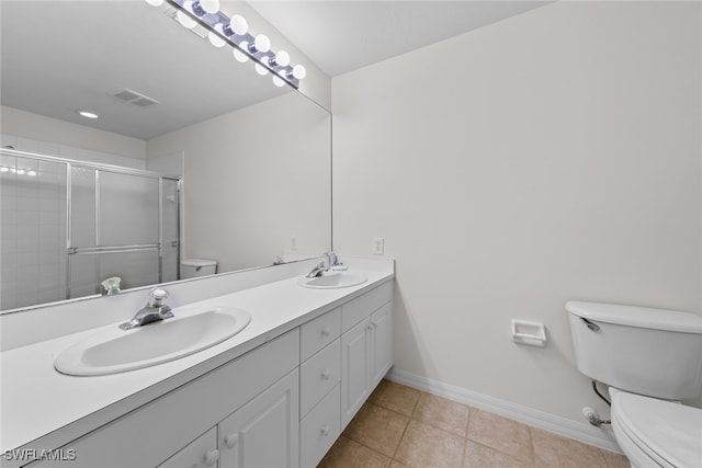 bathroom with tile patterned floors, a shower with door, vanity, and toilet