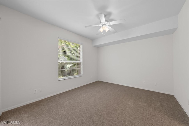 spare room with carpet floors, a ceiling fan, and baseboards