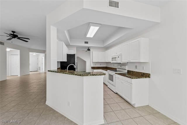 kitchen with white appliances, visible vents, a ceiling fan, white cabinetry, and a tray ceiling