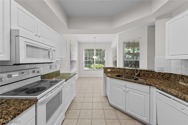 kitchen with dark stone counters, white cabinetry, light tile patterned floors, sink, and white appliances