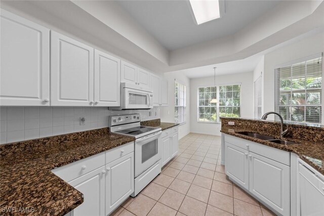 kitchen featuring tasteful backsplash, sink, white cabinets, light tile patterned floors, and white appliances