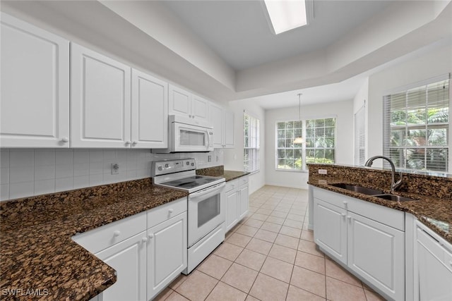 kitchen featuring white appliances, tasteful backsplash, light tile patterned floors, white cabinetry, and a sink