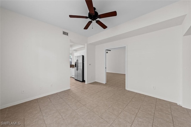 spare room featuring ceiling fan, visible vents, and baseboards