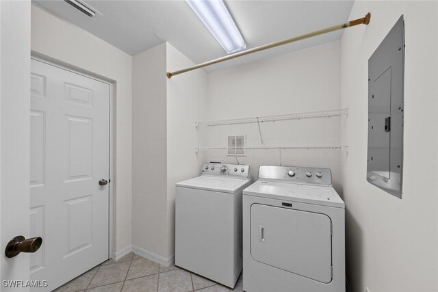 laundry room with washing machine and clothes dryer, electric panel, and light tile patterned floors